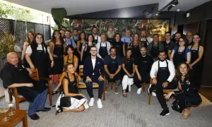 Grupo diverso posa con delantales "es.table Zaragoza" en un evento.