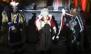 Los Reyes Magos saludan al público en la cabalgata de Reyes de Huesca, con sus trajes brillantes y coronas.