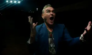 Morrissey en Zaragoza, con gesto dramático y las manos alzadas, bajo luces y una cruz.