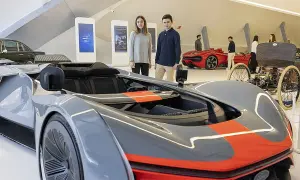 Jóvenes observan coches futuristas y clásicos en una exposición de coches en Zaragoza.