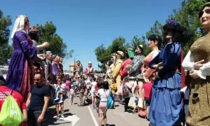Gigantes y cabezudos desfilan en las fiestas del Parque Goya. Niños y adultos disfrutan de la colorida procesión bajo el sol.