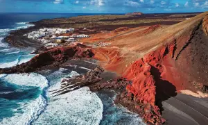Vista aérea de El Golfo, Lanzarote. Un pueblo blanco junto a un cráter volcánico rojo y el mar azul. Imprescindible en tu lista de qué ver en Lanzarote.