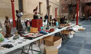 Mercado de antigüedades en Zaragoza con estatuas, jarrones y objetos curiosos en mesas al aire libre.