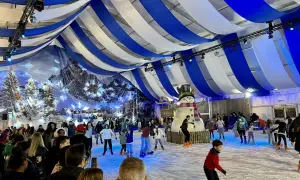 Pista de hielo en Zaragoza, Plaza del Pilar, con un gran muñeco de nieve y gente patinando bajo un techo de telas azules y blancas.
