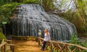Cascada espectacular, ideal para descubrir qué ver cerca de Calatayud. Una mujer sonríe apoyada en una barandilla de madera.