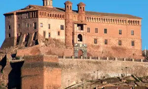 Imponente castillo de ladrillo rojo, con torres y cúpulas, coronando una colina. Un lugar perfecto para imaginar el festival de los castillos.