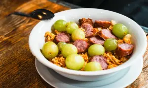 Un plato con uvas verdes, chorizo en rodajas y migas crujientes, un sabor que recuerda a el tubo zaragoza.