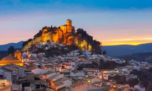 Pueblo blanco andaluz con castillo iluminado en la colina al atardecer. Un lugar encantador que ver cerca de Granada.