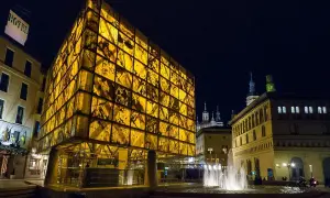 Edificio moderno y translúcido ilumina la noche junto a la fuente, cerca del museo del foro de Caesaraugusta.
