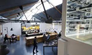 Interior de un restaurante con cocina abierta y estanterías de vino. Un lugar ideal para disfrutar de una experiencia Bib Gourmand en Zaragoza.