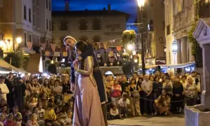 Una pareja se abraza en una calle iluminada por farolas, ante una multitud que observa. Podría ser la escena de "la partida de Diego".