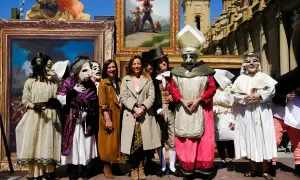 Personas enmascaradas y vestidas con trajes de época posan frente a cuadros, recreando el espíritu de las fiestas goyescas.