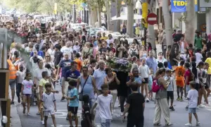 Multitud celebra las fiestas del barrio Las Fuentes en Zaragoza. Una procesión avanza por la calle con gente de todas las edades.