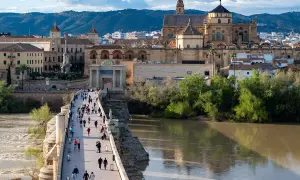 El Puente Romano de Córdoba, con la Mezquita-Catedral al fondo, es lo mejor de Córdoba. Gente pasea por el puente sobre el río Guadalquivir.