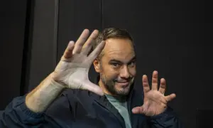 Jorge Blass Zaragoza, ilusionista, sonríe con las manos extendidas, listo para un truco.