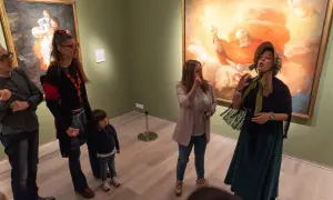 Un grupo de personas, incluyendo una niña, disfruta de una visita guiada en el **Día de los Museos Zaragoza**, admirando obras de arte.