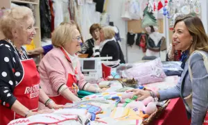 Sonríen vendedoras en el mercadillo Ozanam Zaragoza, mostrando textiles y peluches.