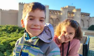 Dos niños sonríen frente a un palacio en Zaragoza. ¡Una aventura familiar en el museo!