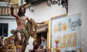 Imagen de una escultura de Cristo en una procesión de Martes Santo. La figura, con corona de espinas dorada, porta una túnica dorada y levanta una mano.