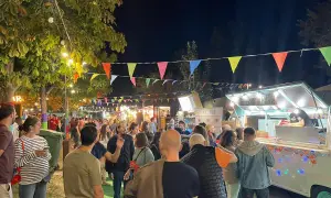 Noche animada en un festival de ebro food trucks, con luces, banderas y gente disfrutando.