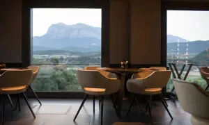 Mesas y sillas en un restaurante con vistas a montañas y valles, como si fueran soles Repsol en Aragón.