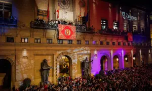 Multitud celebra el pregon de pilares en Zaragoza. Gente en balcones y plaza, luces y banderas.