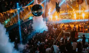 Multitud bailando en una discoteca con luces de neón, humo y una bola de discoteca, celebrando la nochevieja en Zaragoza.