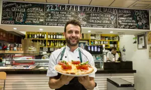 Chef sonriente en Zaragoza ofrece una pizza artesana. ¡Los soletes Repsol de esta pizzería son deliciosos!