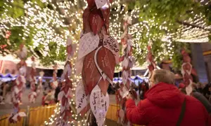 Árbol de deseos en el mercadillo de Navidad de Zaragoza, cubierto de hojas con mensajes y luces festivas.