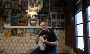 Un hombre sonriente con un banjo en salsipuedes una tasca encantadora, rodeado de carteles vintage y objetos curiosos.