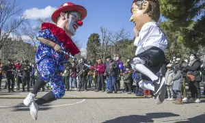 Gigantes y cabezudos saltan en una fiesta popular. Un payaso y un hombre con boina roja celebran el 5 de marzo.