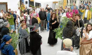 Gente celebra la fiesta de las brujas en Trasmoz. Mujeres vestidas de negro y con sombreros de bruja, rodeadas de hierbas y flores.