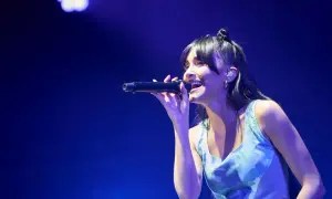 Aitana Zaragoza canta con pasión en un concierto, iluminada por luces azules.
