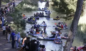 Gente en balsas y kayaks disfrutan de la bajada del canal, rodeados de espectadores en la orilla.