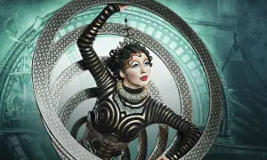 Artista del circo del sol en Zaragoza, con un traje de rayas doradas y negras, dentro de un aro metálico con intrincados diseños.