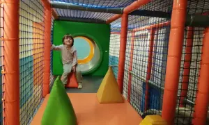 Niño sonriente en un divertido parque de bolas en Zaragoza, rodeado de redes y conos de colores.