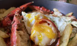 Deliciosos huevos rotos con bogavante, patatas fritas crujientes y un huevo con la yema perfecta.