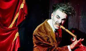 Actor con maquillaje de terror y traje marrón muerde un puro, listo para el circo del terror Zaragoza.