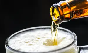 Cerveza dorada cayendo de una botella a un vaso espumoso. ¡Una birra Zaragoza perfecta para refrescarse!