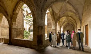Un grupo visita el claustro del monasterio de la Resurrección en Zaragoza, admirando su arquitectura y vegetación.