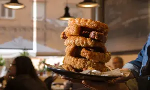 Torre de torrezno crujiente, ¡el mejor torrezno de Zaragoza! Servido en plato negro, listo para disfrutar.