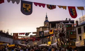 Gente disfrutando del mercado de las tres culturas Zaragoza, con pendones y una noria de madera.