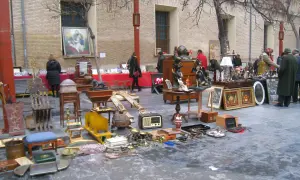 Mercadillo en la plaza San Bruno con antigüedades, muebles y objetos decorativos expuestos en el suelo y mesas.