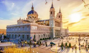 Catedral de la Almudena, uno de los **lugares para conocer en Madrid**, con gente paseando en una tarde soleada.