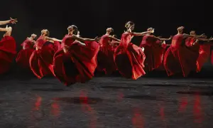 Danzarinas con vestidos rojos vibrantes en el escenario, evocando la fuerza de Carmina Burana en Zaragoza.