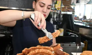 Camarera sirviendo crujiente chicharrón, perfecto para comer en carretera cerca de Zaragoza.