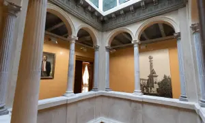 Interior del palacio de Armijo con arcos, columnas y un retrato.