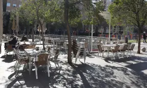 Mesas y sillas vacías en la terraza de bares de la plaza San Francisco, bajo la sombra de los árboles.
