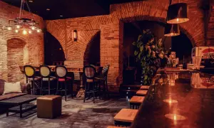 Ambiente acogedor en la praga vermuteria, con ladrillos expuestos, luces cálidas y cómodos asientos.