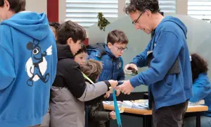 Niños observan una linterna mágica en Zaragoza, aprendiendo sobre su funcionamiento.